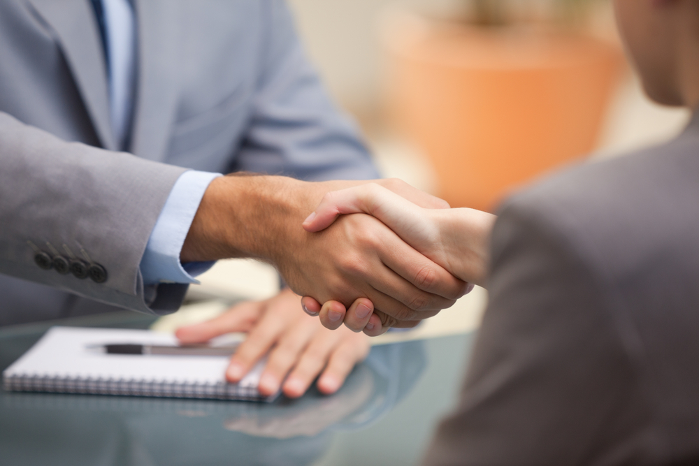Two Businesspeople shaking hands indoors Two Businesspeople shaking hands indoors